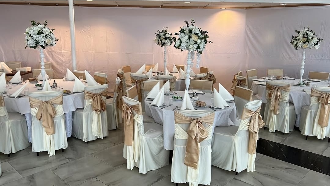 Dukning med vita dukar, champagnefärgade stolsrosetter vita höga blomsterarrangemang i vitt