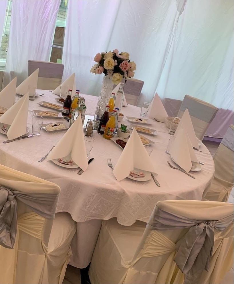 Sofistikerade toner av vitt, silver och puderrosa. Runda bord klädda i lyxiga textilier, sidenrosetter på stolarna och eleganta blomsterarrangemang