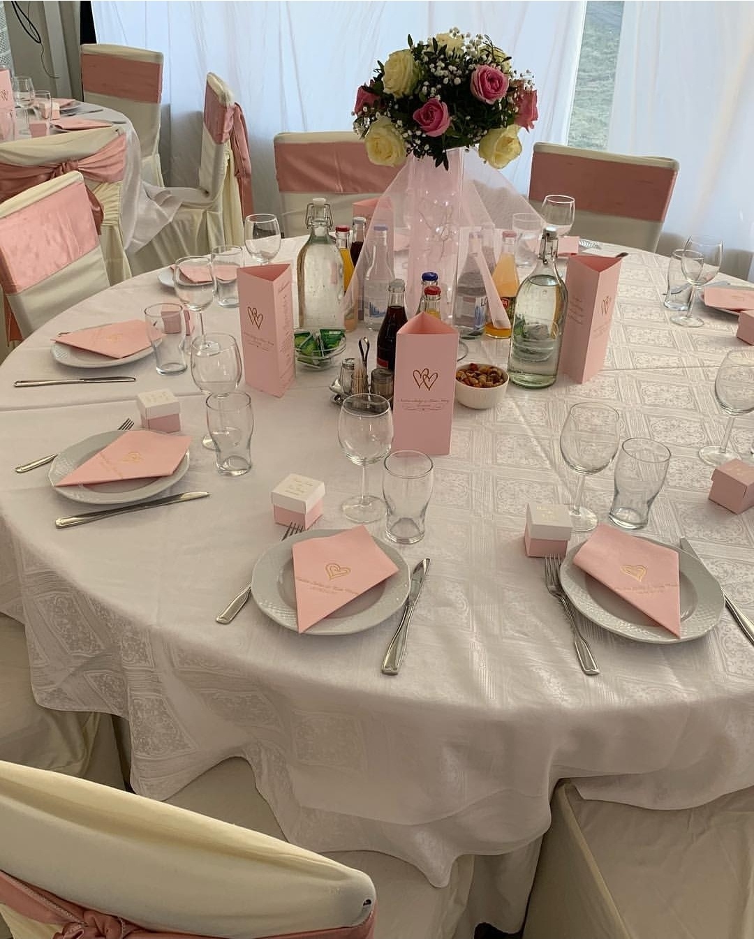 Elegant vitt och pudrigt rosa med runda bord, skräddarsydda stolsöverdrag och mjuka sidenrosetter. 